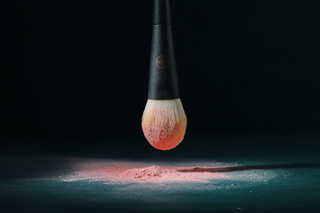 A close-up of a makeup artist blending contour on a model's face with brushes and makeup products in the background.