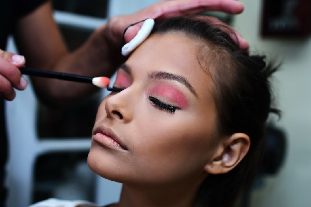 A close-up of a makeup artist applying contour makeup on a model's cheekbones, showcasing the application technique and products used.